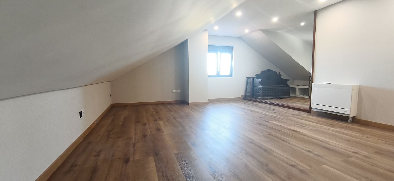 Salón abuhardillado y luminoso con suelo de madera